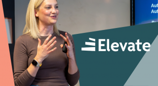 Image is of a woman speaking to an audience participating in training, with a presentation running in the background, the logo 'Elevate' to the right